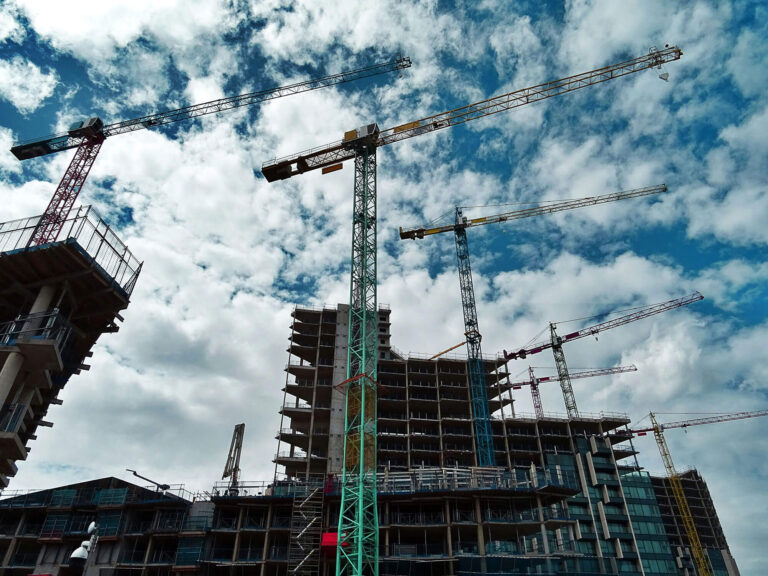 Construction site with cranes and scaffolding against a cloudy sky, highlighting major construction projects related to scaffolding and access solutions.